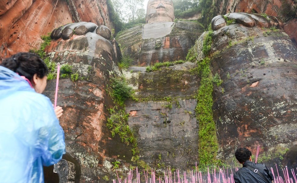 Tourists burn offerings at the feet of the Giant Buddha in 2016