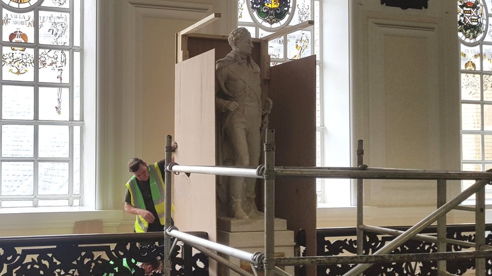 Рабочий боксирует со статуей сэра Томаса Пиктона в мэрии Кардиффа