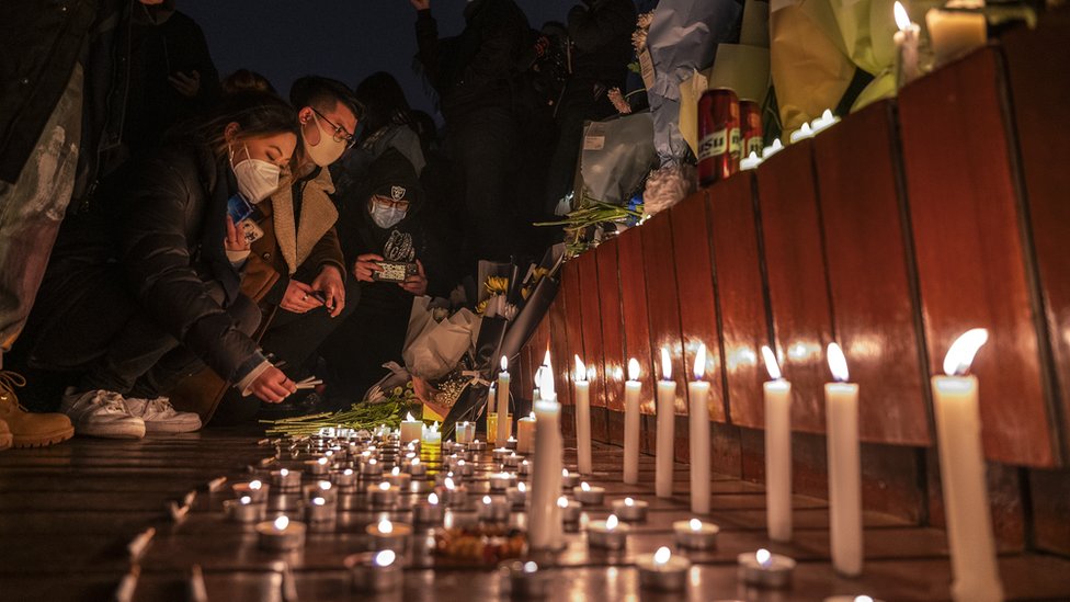 2022年11月27日，北京抗議者在為烏魯木齊公寓火災的遇難者舉行的悼念活動上點燃蠟燭並留下香煙。