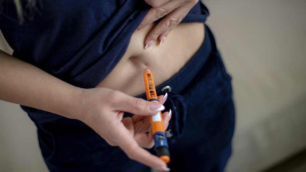 Una mujer se aplica una inyección subcutánea en el abdomen.