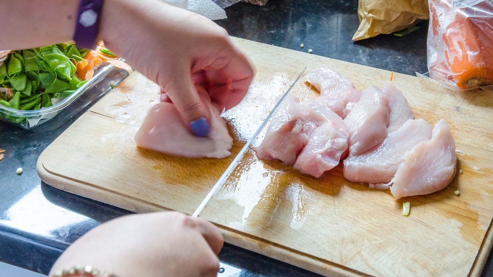 mujer cortando pollo