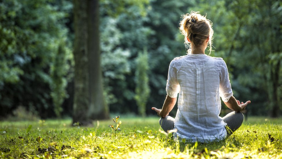 Mujer meditando en un parque.