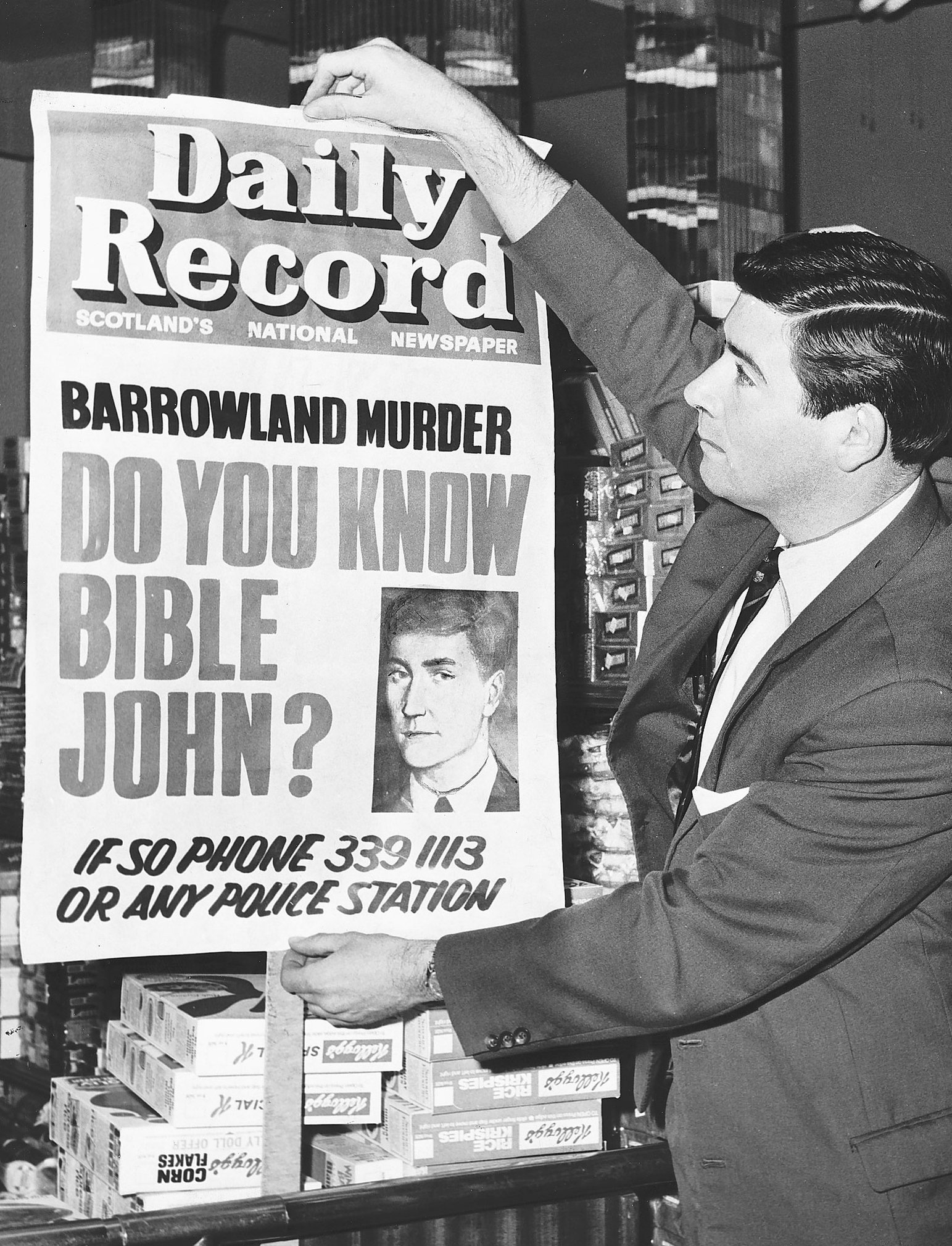 Un hombre cuelga un cartel de la búsqueda de John Biblia.