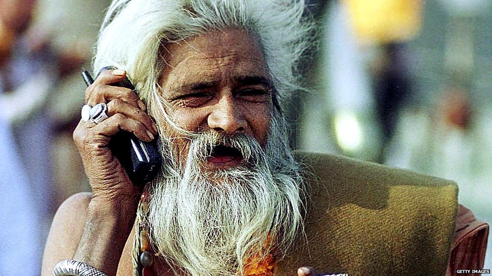 Садху пользуется мобильным телефоном во время Маха Кумбха Мела в Праяге в Аллахабаде