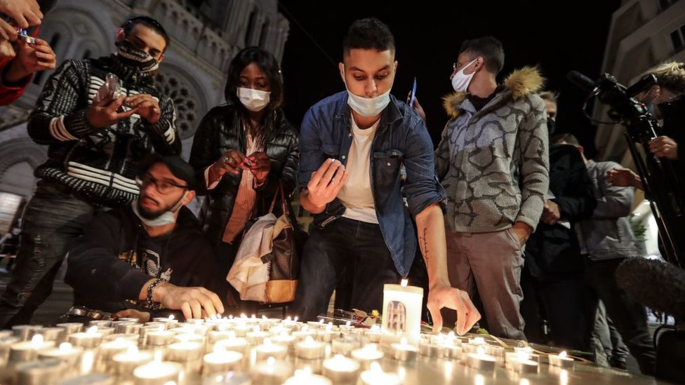 People lights candle outside the Notre-Dame de l`Assomption Basilica in Nice on October 29, 2020