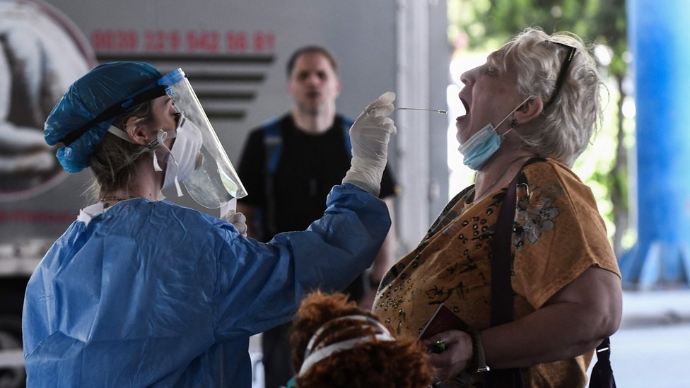 Работник общественного здравоохранения собирает мазок у женщины для тестирования на коронавирус COVID-19 на греко-болгарском пограничном переходе в Промахонасе 19 июня 2020 г.