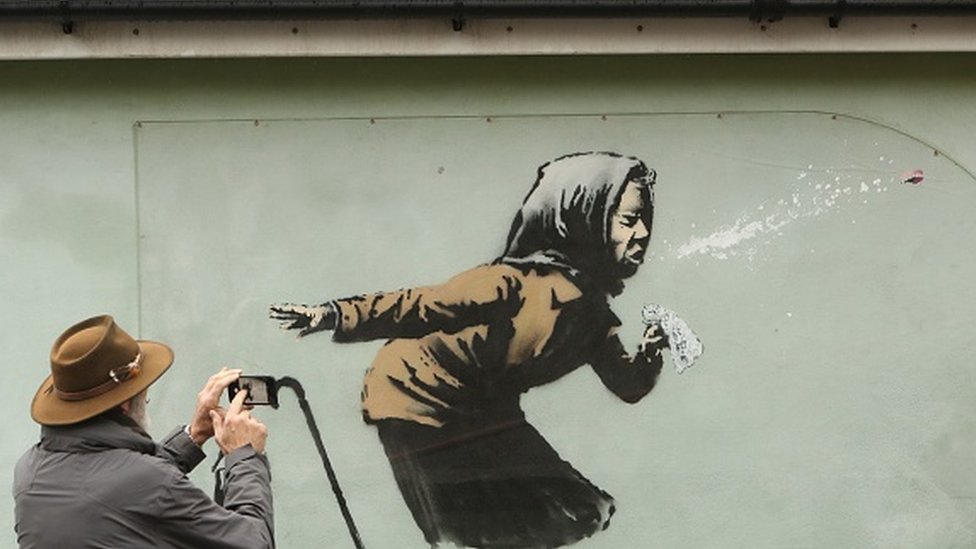 Homem tira foto de grafite de uma mulher espirrando