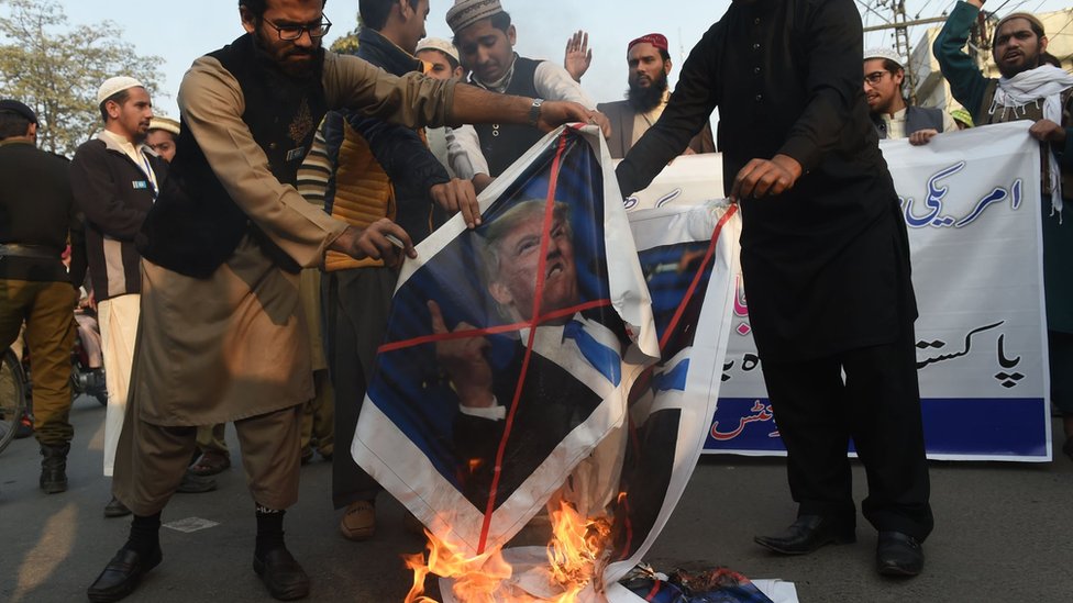 Пакистанские демонстранты сжигают изображения президента США Дональда Трампа и флага США во время акции протеста против сокращения помощи США в Лахоре 5 января 2018 года.