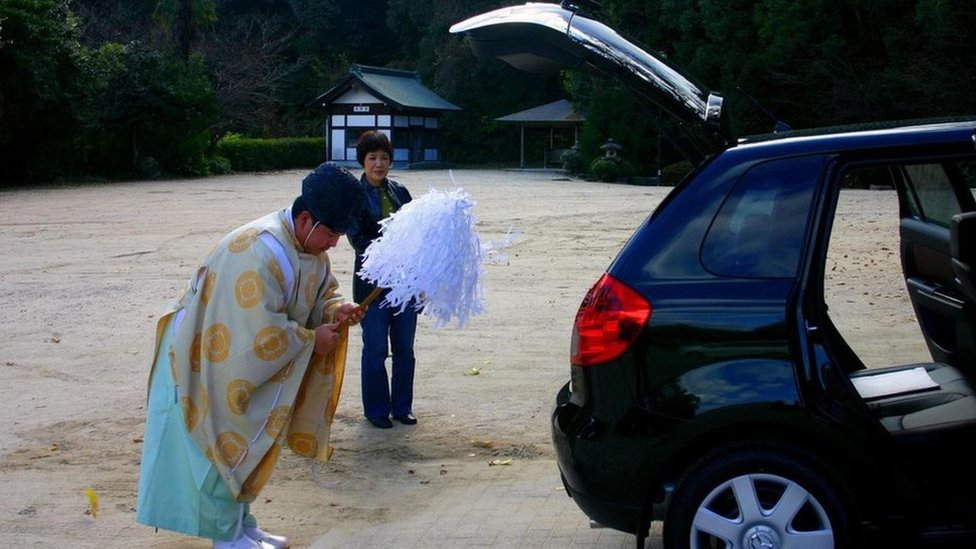 Un sacerdote sintoísta purificando el auto nuevo de una japonesa.