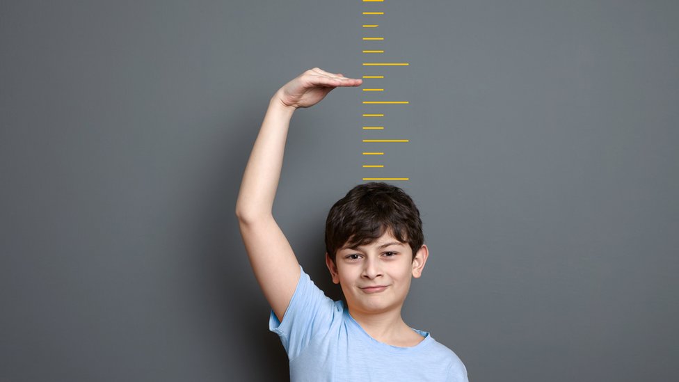Boy trying to work out how tall he could grow