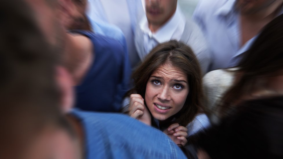Una mujer visiblemente afectada en medio de una multitud.
