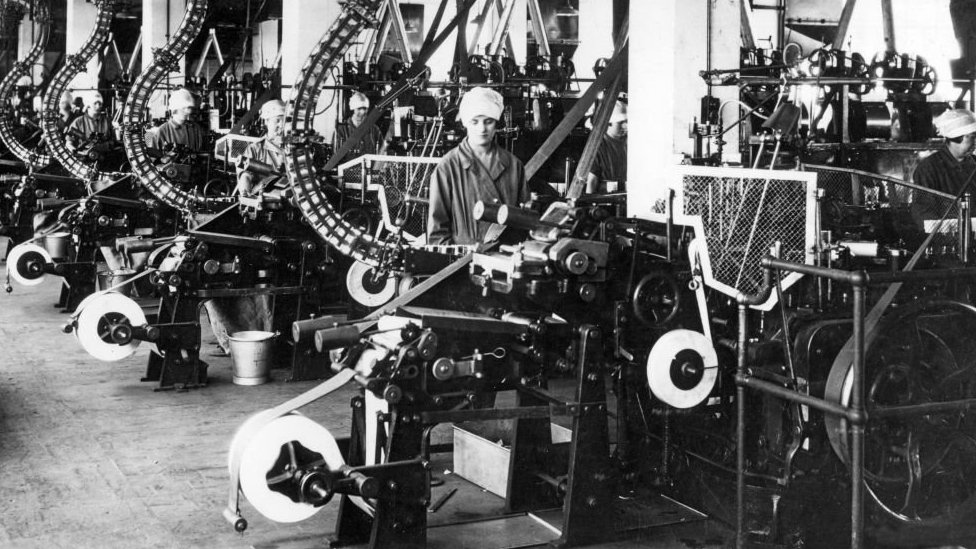 flu, flu spanyol, pandemi, virus corona, Woman at an assembly line in a UK factory in the 1920s