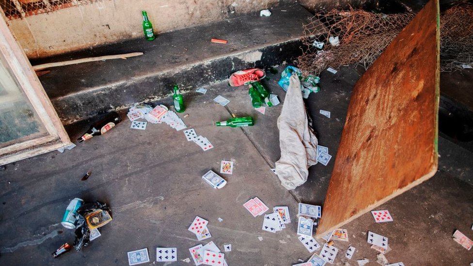 Карты и пивные бутылки лежат на полу в неформальном месте для азартных игр после того, как полицейская служба ЮАР (SAPS) арестовала 8 человек за нарушение правил изоляции и ограничения на алкоголь в Хиллброу, Йоханнесбург, 27 марта 2020 года.