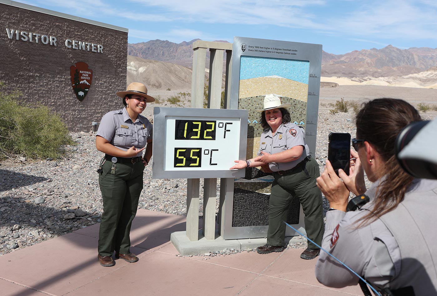 National Park Service Rangers stand next to a digital display of an unofficial heat reading at Furnace Creek Visitor Center in Death Valley National Park, California - 16 July 2023