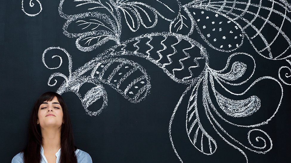 Young woman standing against a wall with chalk drawings