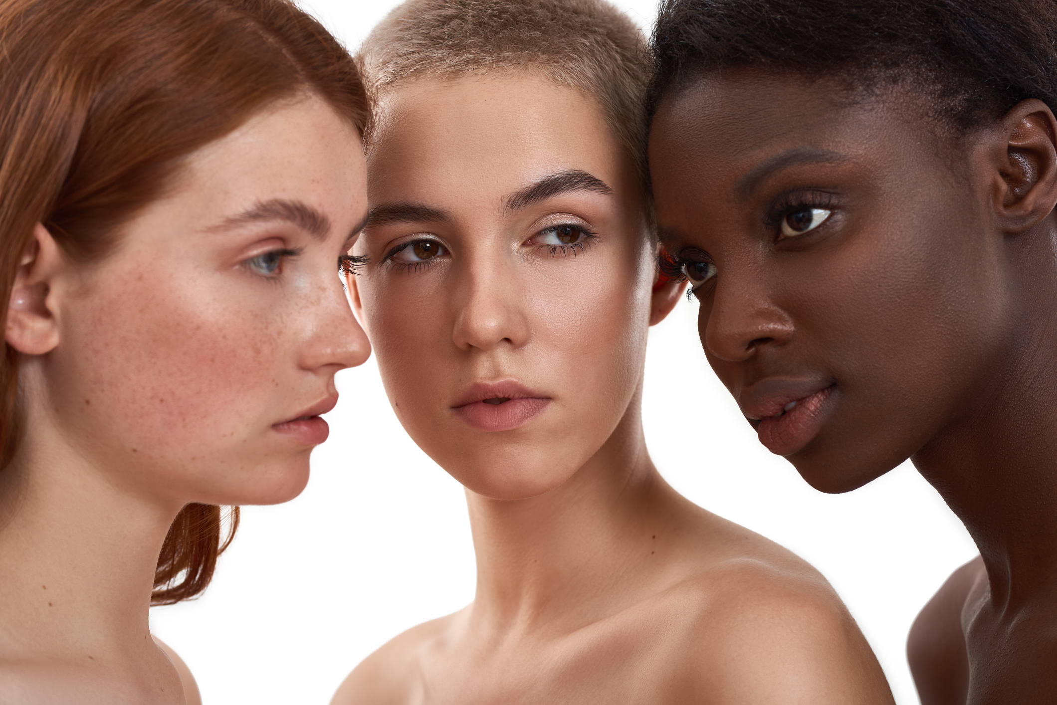 Tres mujeres cuyas pieles tienen tres tonalidades distintas se miran unas a las otras.