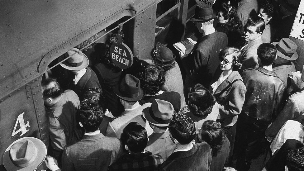 Пассажиры в час пик садятся в поезд метро Sea Beach с переполненной платформы на Таймс-сквер в Нью-Йорке