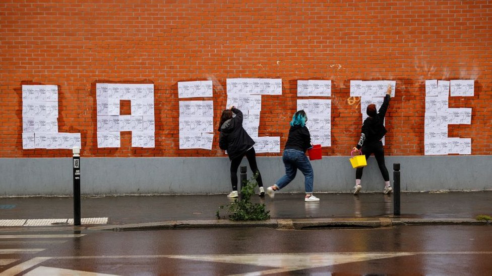 Tres mujeres pintando la palabra laicidad en una pared.