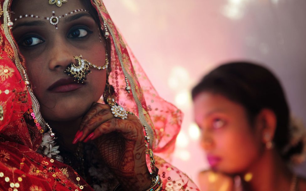 Индийская невеста (слева) вместе со своей сестрой (справа) ждет свадебной церемонии.