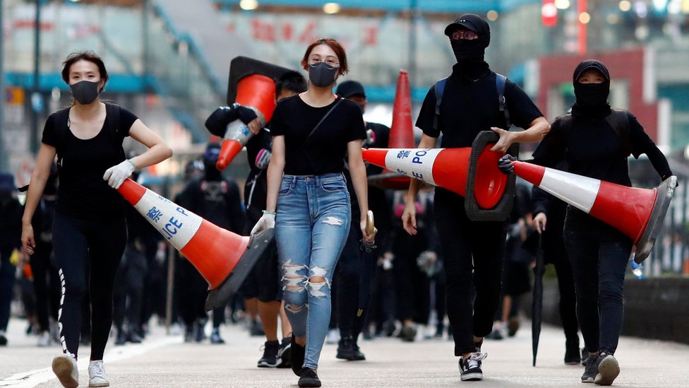 Протестующие идут по дороге с дорожными конусами, чтобы построить баррикаду в Козуэй-Бэй, Гонконг, Китай 11 ноября 2019 г.