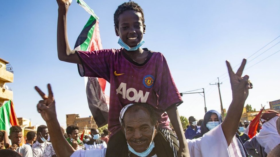 متظاهر يحمل فتى على كتفيه في احتجاج في السودان يوم الخميس 25 تشرين الثاني/نزفمبر 2021