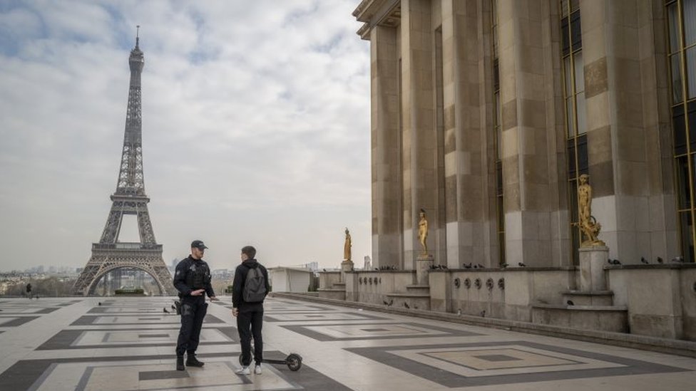 Полицейские допрашивают водителя скутера, проезжающего возле Эйфелевой башни через несколько часов после введенного правительством карантина 17 марта 2020 года в Париже, Франция