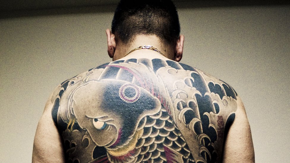 Hombre con tatuajes en su espalda
