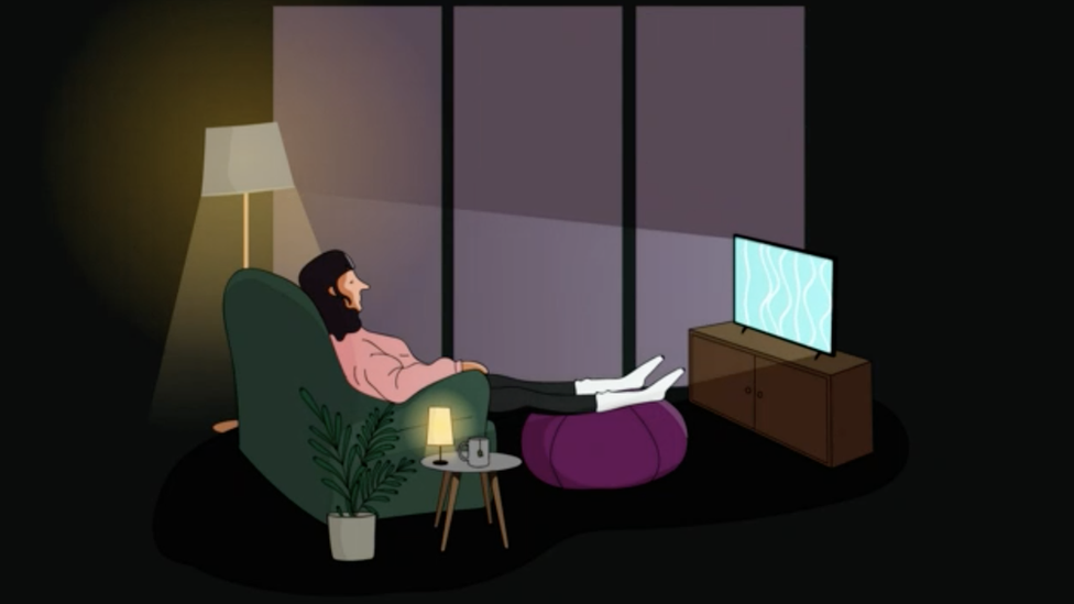 A woman watching TV closely at night
