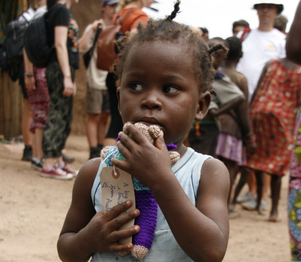 Ребенок в Африке с вязанным плюшевым мишкой