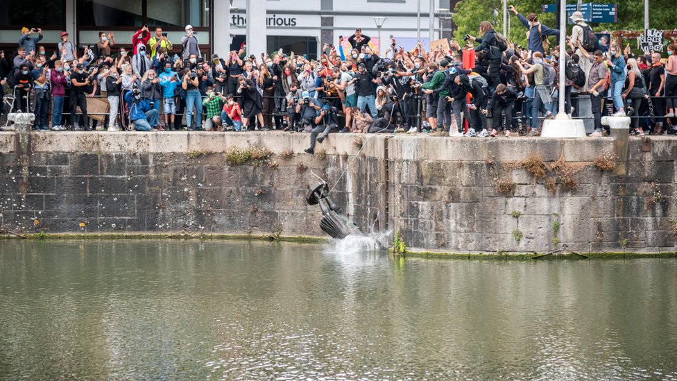 Статуя Эдварда Колстона падает в воду после того, как протестующие сбросили ее и столкнули в доки,