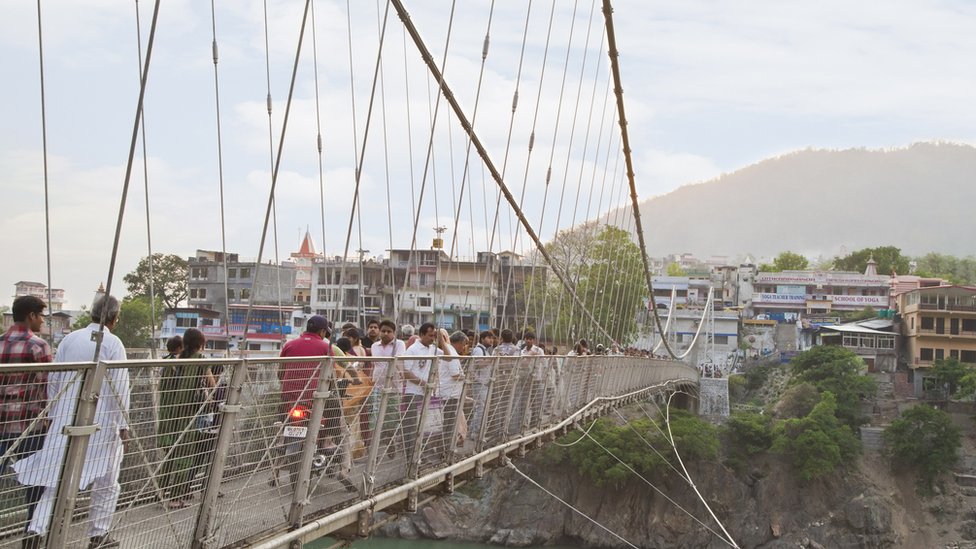 Tourists stand on the Lakshman Jhula suspension bridge