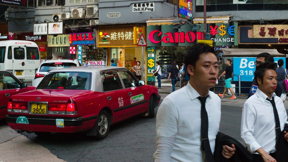 Пешеходы проходят мимо магазинов в районе Тим Ша Цуй в Гонконге в 2016 году