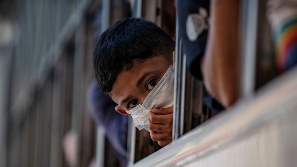 A boy wearing a facemask peers out from the window of a bus about to leave Manila before it is placed on lockdown on March 13, 2020 in Quezon city, Metro Manila, Philippines.