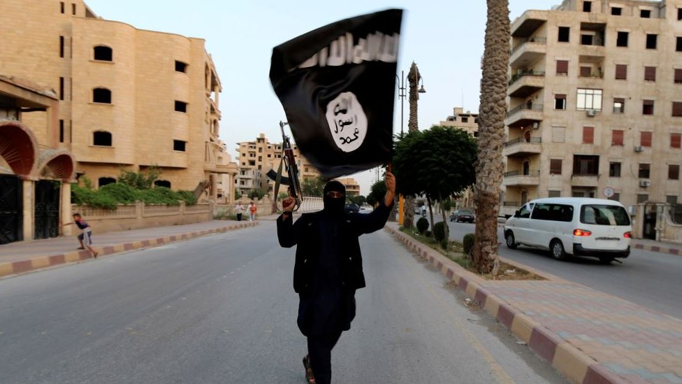 maskiran čovek sa zastavom ISIS-a u Iraku