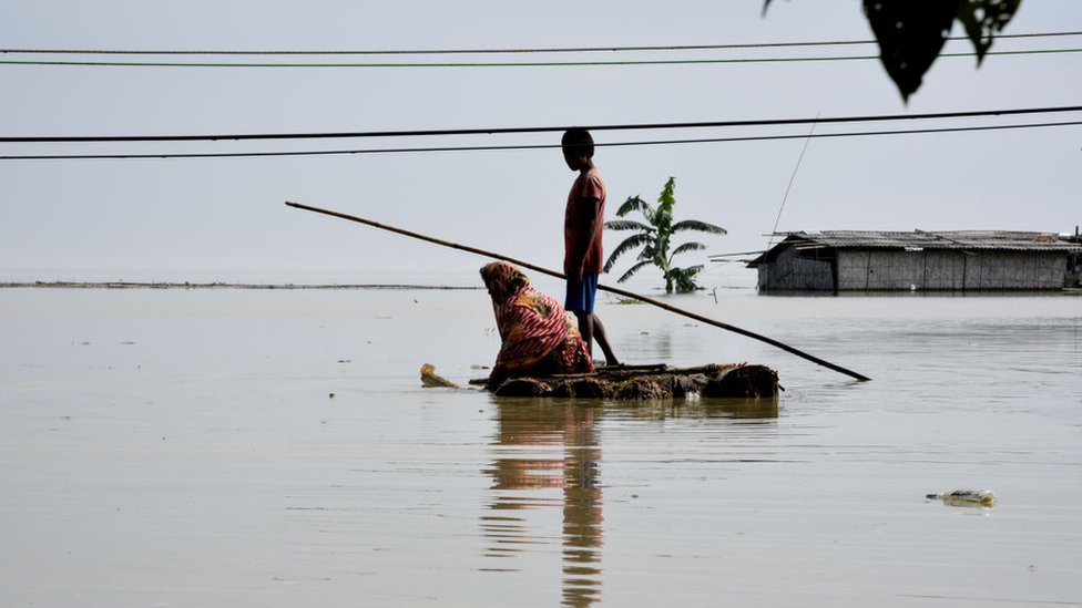 Жители деревни пересекают затопленную территорию на импровизированном плоту в деревне Паникайти в районе Камруп, штат Ассам, Индия, во вторник, 14 июля 2020 г.