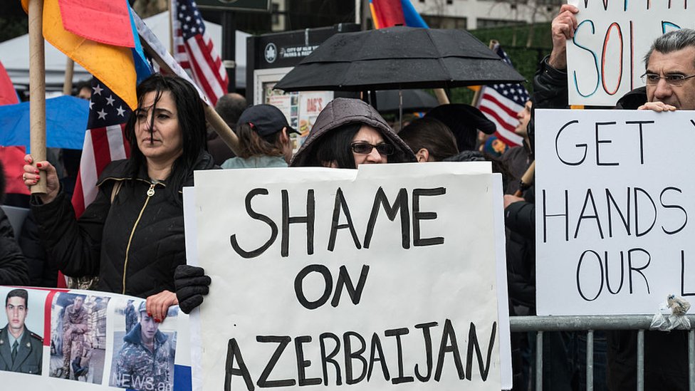 Armenian protesters hold a sign saying Shame on Azerbaijan