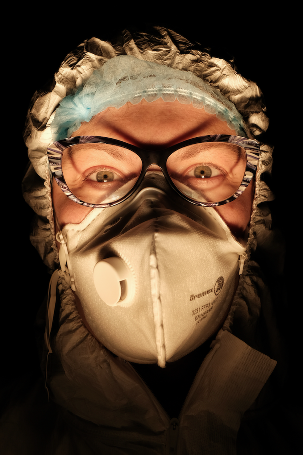 Una enfermera con la cara cubierta con una máscara en un entorno oscuro