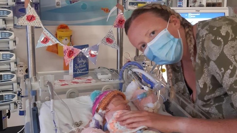 Шарлотта Тейлор гладит свою маленькую дочку в больничной кроватке