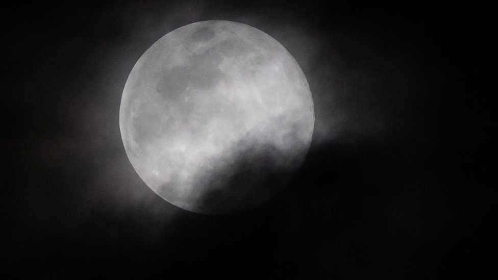 The super worm moon partly covered in cloud