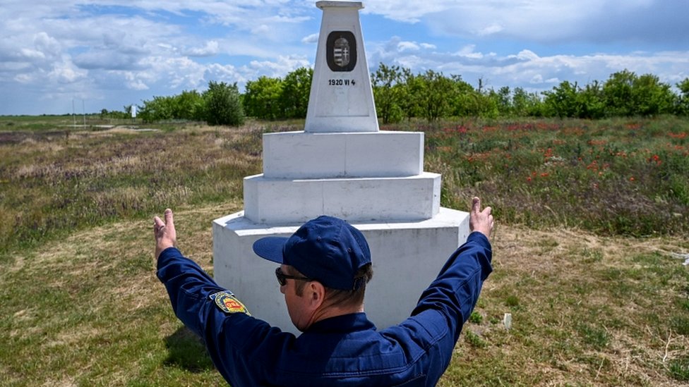 Пограничник стоит рядом с треугольной каменной колонной, обозначающей место, где встречаются границы Венгрии, Румынии и Сербии в Кубехазе недалеко от Сегеда 25 мая 2020 года