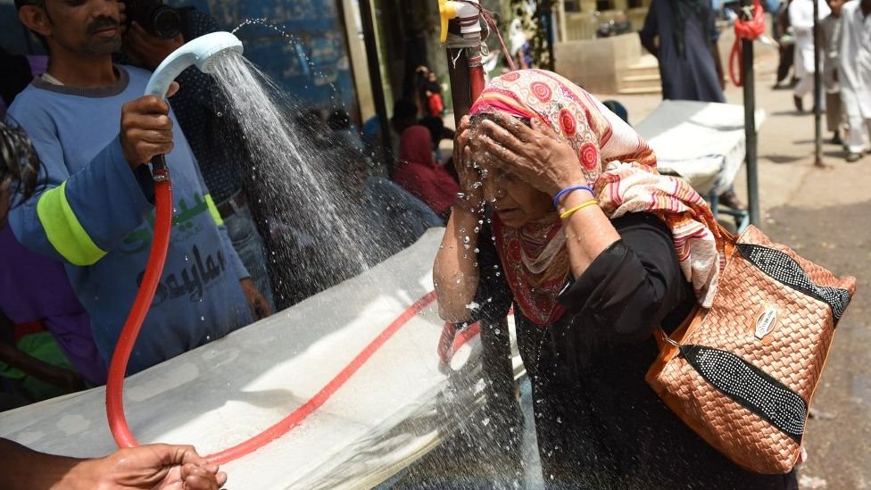 A Pakistani volunteer showers a woman with water during a heatwave in Karachi
