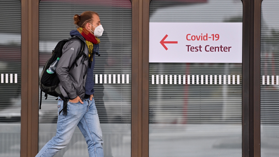 A man walks past a sign for a covid test centre, in Berlin