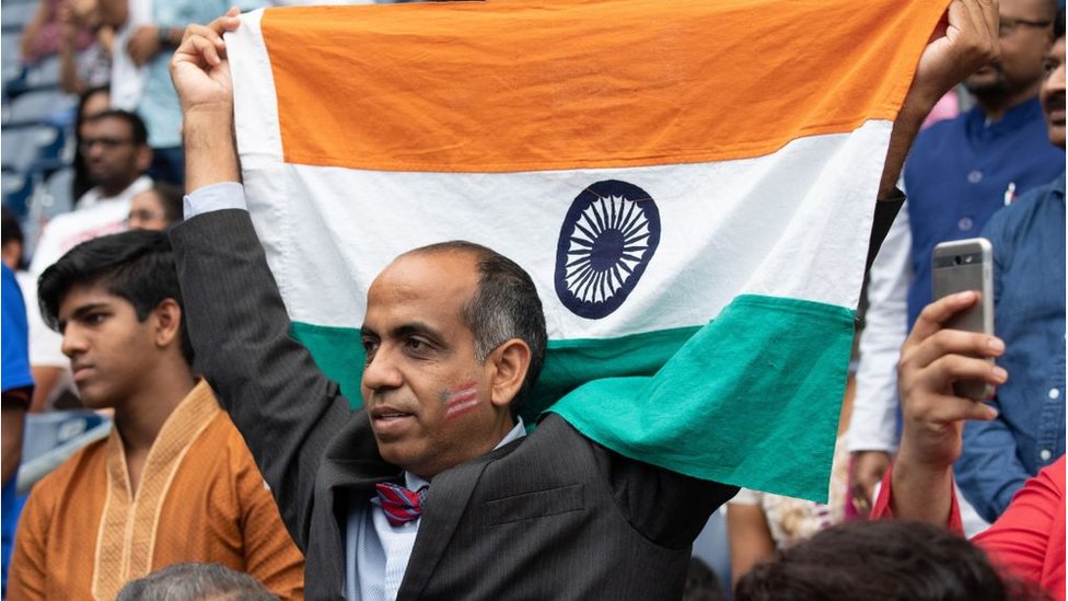 Мужчина держит флаг Индии, когда президент США Дональд Трамп и премьер-министр Индии Нарендра Моди присутствуют на «Привет, Моди!» на стадионе NRG в Хьюстоне, штат Техас, 22 сентября 2019 г.