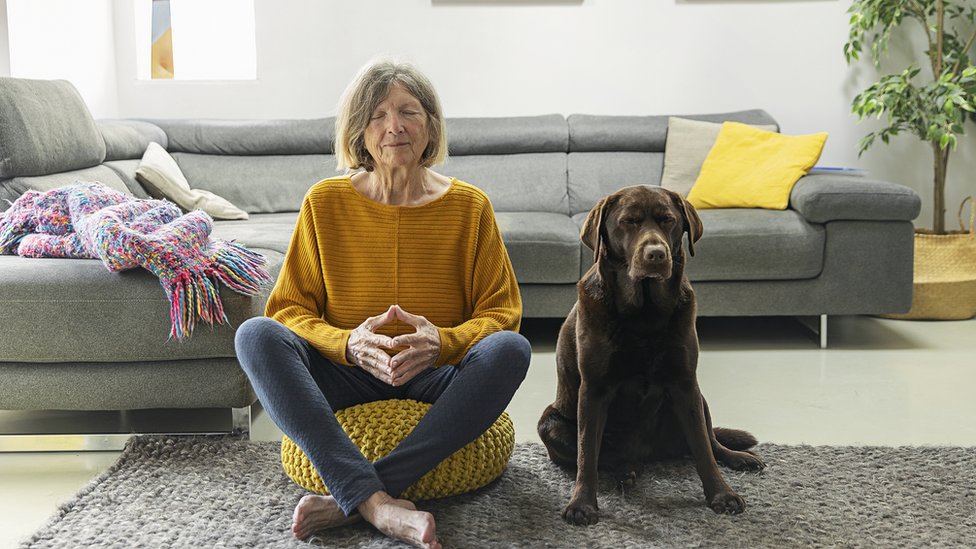 Mujer meditando junto a su perro.