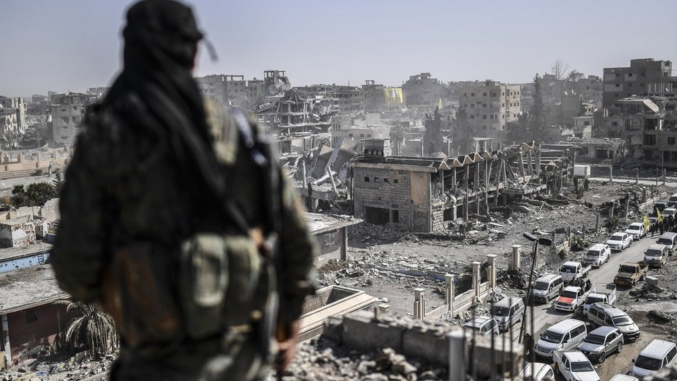 Боец Сирийских демократических сил стоит на страже на крыше в Ракке после того, как отбил город у Исламского государства