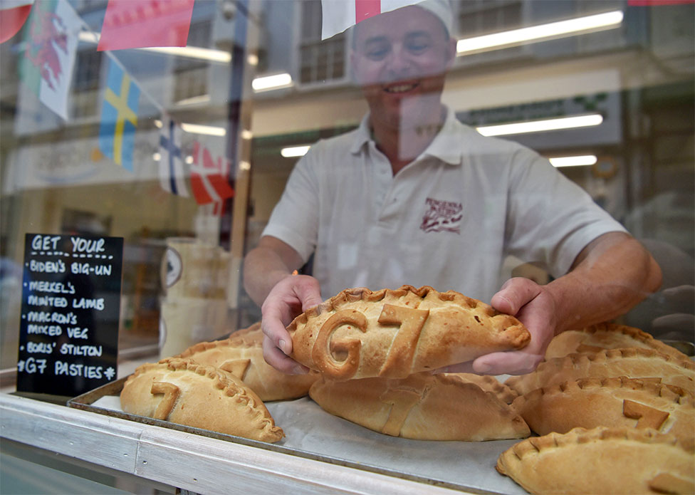 A baker puts a pasty in his shop window with G7 marked in pastry
