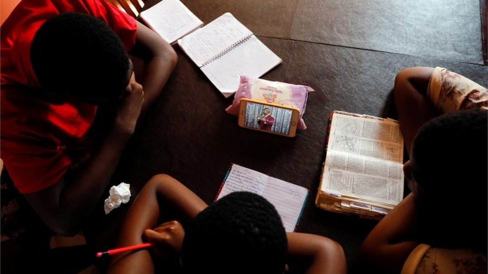 Подростки смотрят прямую трансляцию церковной службы из дома, поскольку все религиозные собрания приостановлены из-за опасений по поводу распространения коронавирусной болезни (COVID-19) в Аккре, Гана, 22 марта 2020 г.