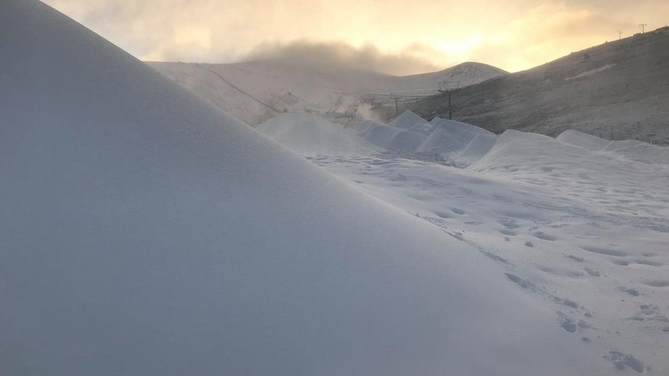 Искусственный снег с настоящим снегом на холмах на заднем плане у горы Кэрнгорм