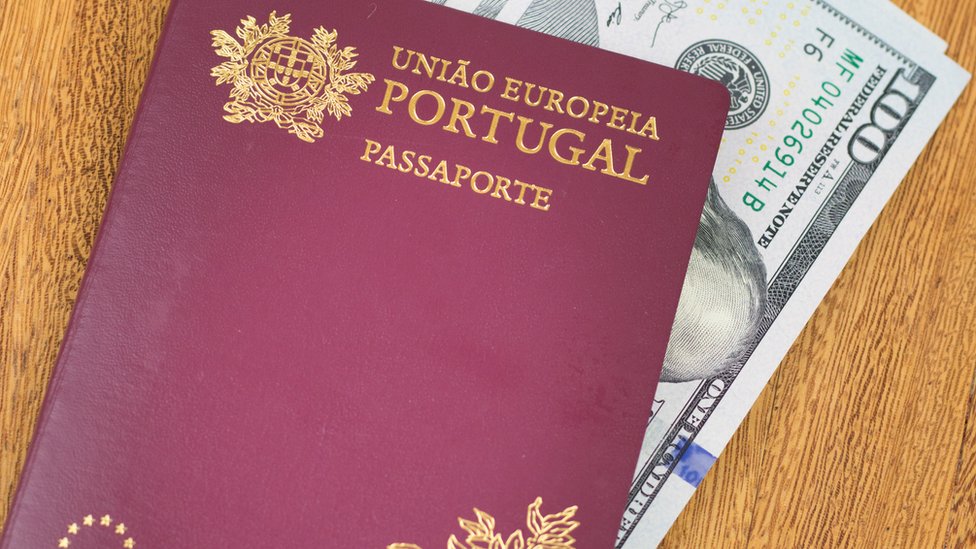 Un pasporte portugués con unos billetes de 100 dólares dentro.