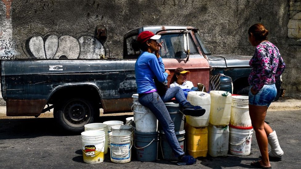 Mujeres en Venezuela esperando para llenar tanques de agua.